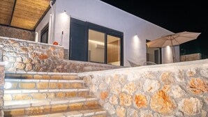A stone staircase leading to a modern building with a glass door and an umbrella.
