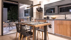 A modern kitchen with a dining area, large windows, and a washing machine.