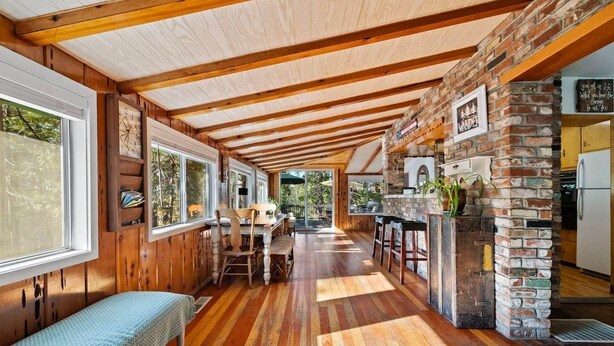 A rustic interior with wooden beams, a stone fireplace, and a wooden dining area. - Walk to town, Lake access, Pet Friendly, King bed (Twain Harte)