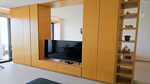 Een moderne woonkamer met een ingebouwde televisie, houten lambrisering en een klein bijzettafeltje.