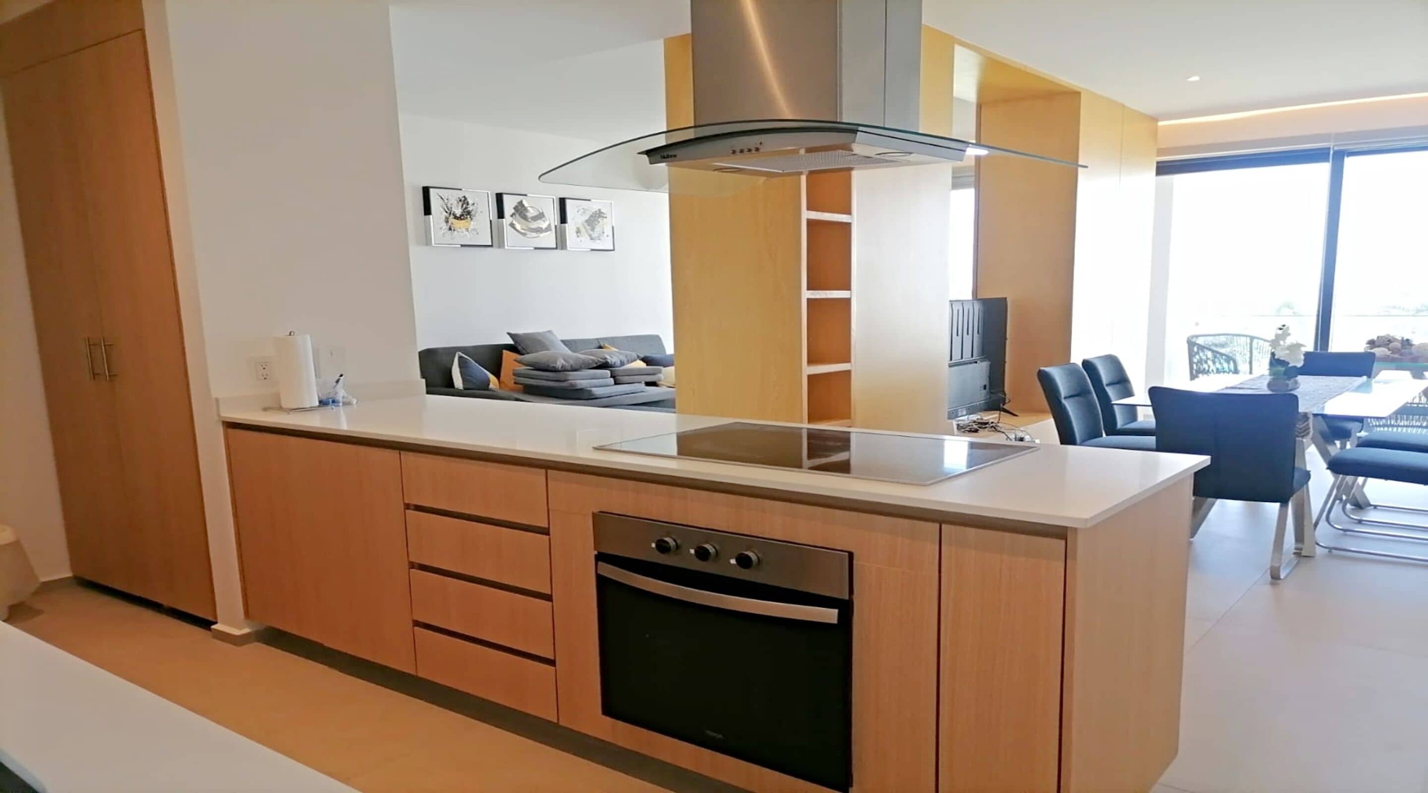 Una cucina moderna con forno integrato, lavastoviglie e cappa aspirante in acciaio inossidabile. Si nota anche un'area pranzo con tavolo e sedie sullo sfondo.