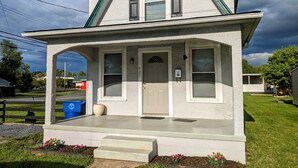 Ein zweistöckiges Haus mit Veranda, Garage und einem gepflegten Rasen.