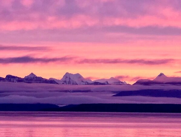 A mountainous landscape with snow-capped peaks and a body of water reflecting the sky. - Sea,Sunrises,Sauna | Oceanfront Stylish Retreat (Campbell River)