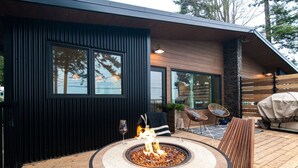 Un patio extérieur moderne doté d’un foyer circulaire, d’un espace salon et d’une terrasse en bois.