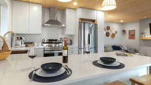 Une cuisine moderne avec des meubles blancs, des appareils en acier inoxydable et un îlot central aménagé en coin repas.