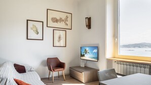 A modern room with a bed, a TV, a chair, and a table.