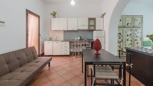 Un espacio habitable compacto con kitchenette, comedor y sofá.