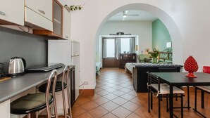 Una cocina con comedor, una cafetera y un adorno rojo sobre la mesa.