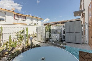Ein Wohnhausgarten mit Schwimmbad, weißem Zaun, Kakteen und einer Holzterrasse.