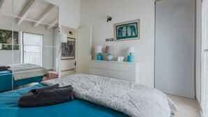 A bedroom with a bed, a dresser, a mirror, and a door.
