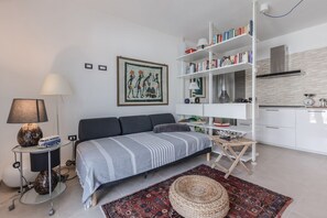 Ein modernes Wohnzimmer mit einer Couch, einem Bücherregal, einer Lampe und einem Teppich.