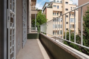 Un balcon étroit doté d’une rambarde en métal, d’un mur végétal et offrant une vue sur les bâtiments voisins.