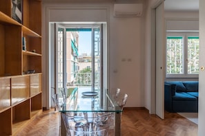 Una sala moderna con una mesa de comedor de cristal, un sofá azul y una estantería de madera.