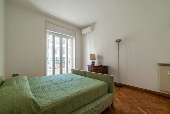 Une chambre à coucher avec un lit, une commode, une lampe de chevet et une lampe sur pied.