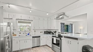 Una cocina moderna con armarios blancos, electrodomésticos de acero inoxidable y suelo de madera.