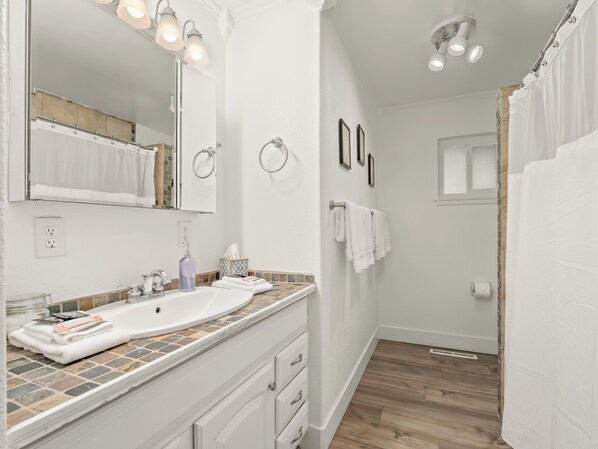 A modern bathroom with a large mirror, two sinks, a shower, and a toilet.