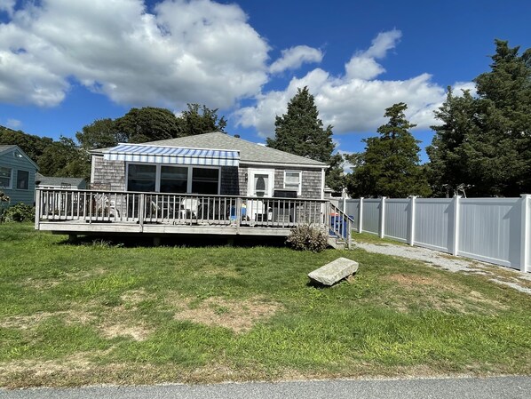 A single-story house with a covered porch and a fenced yard. - Spacious Cottage (Mattapoisett)