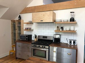 A compact kitchen with a gas stove, oven, microwave, and toaster.