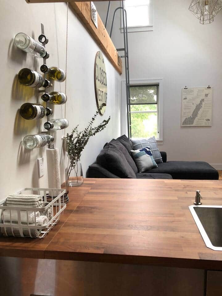 Une cuisine dotée d’un plan de travail en bois, d’un évier et d’un porte-bouteilles fixé au mur.