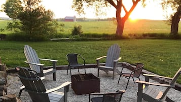 Un espacio al aire libre con sillas Adirondack y una fogata.
