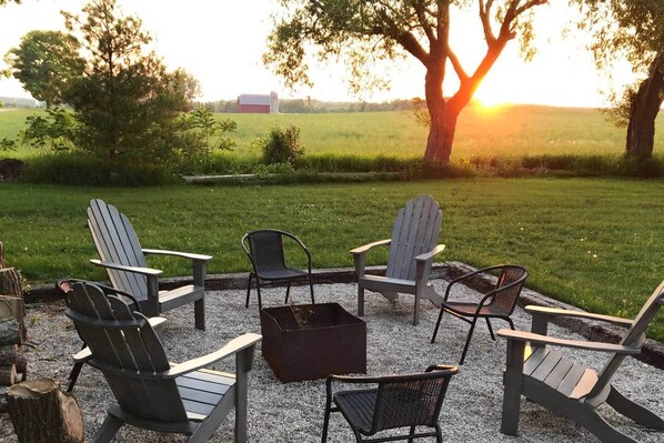 An outdoor seating area with Adirondack chairs and a fire pit.