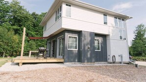 A two-story house with a covered patio and a grill. - Sister Bay Eclectic Cottage (Sister Bay)
