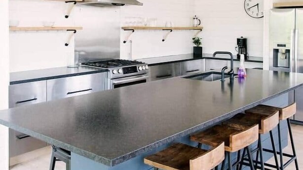 A modern kitchen with a large island, bar stools, pendant lights, and stainless steel appliances. - Sister Bay Eclectic Cottage (Sister Bay)