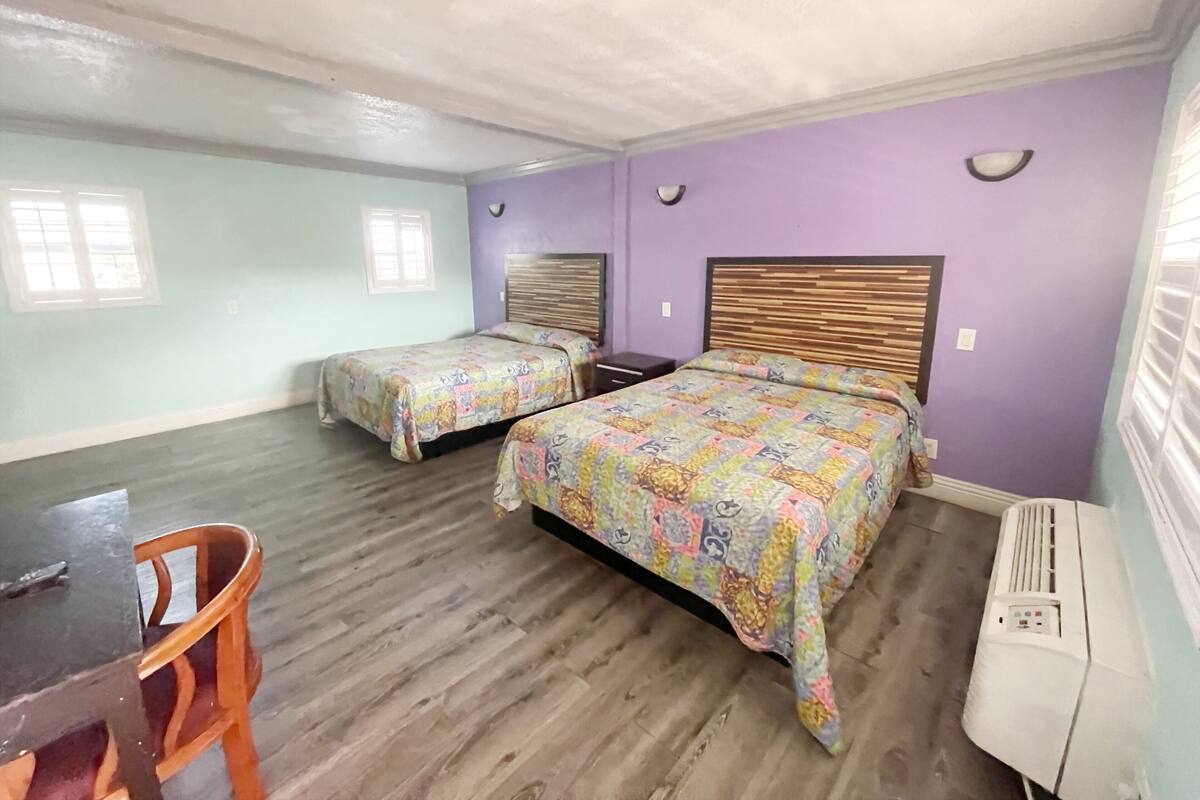 A room with two beds, a desk, and a chair.