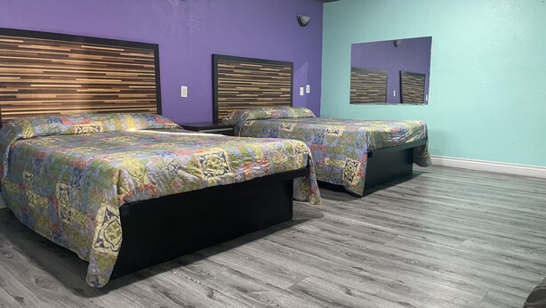 Quarto com duas camas, cada uma com colcha estampada, cabeceiras de madeira e parede verde claro.