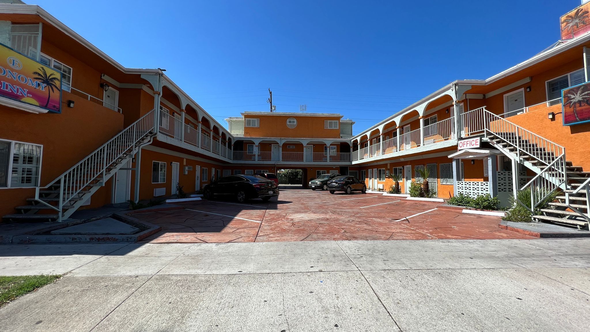 A hotel with a central courtyard, multiple balconies, and a parking area.