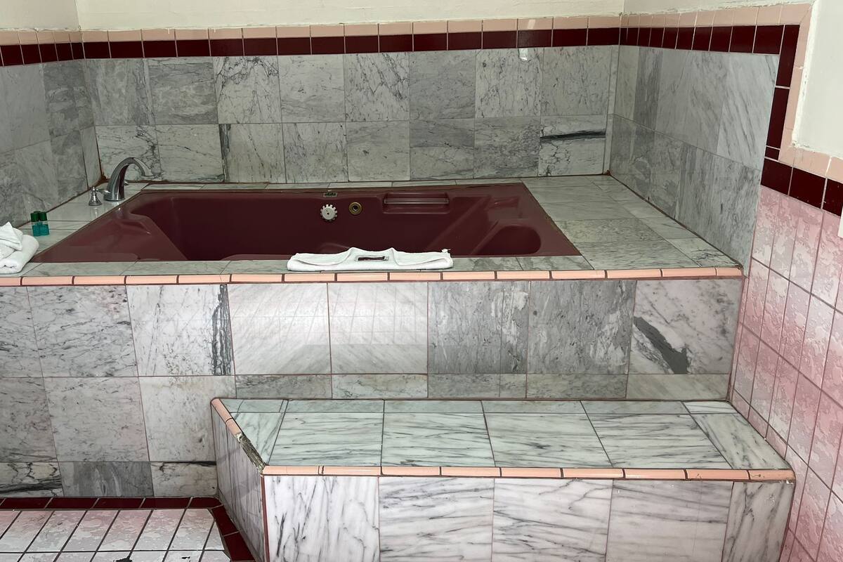 A bathroom with a marble bathtub, a shower area, and a toilet.