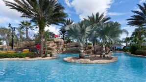 Une piscine bordée de palmiers, avec un décor rocheux en arrière-plan.