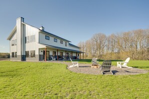 A modern two-story house with a large porch and outdoor seating area.