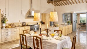Eine geräumige Küche mit Holzschränken, einer großen Kochinsel und einem Essbereich, der für eine Mahlzeit gedeckt ist.