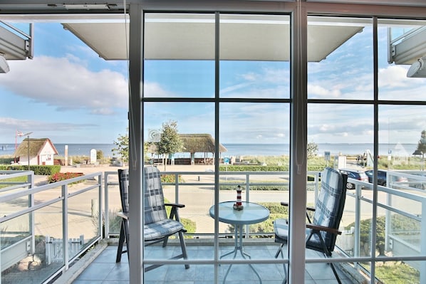 Ein Balkon mit Meerblick, ausgestattet mit zwei Stühlen und einem kleinen Tisch.