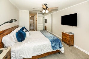 Ein Schlafzimmer mit einem Bett, einem Deckenventilator, einem Fernseher und einem Nachttisch.