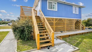 Et tosidet, blåt hus med en trætrappe, der fører op til en terrasse.