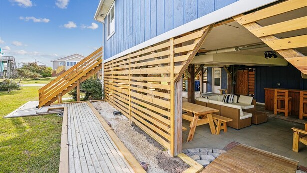 En træterrasse med udendørs møbler og en trappe til en overdækket patio.