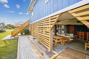Une terrasse en bois avec des sièges extérieurs et un escalier menant à un patio couvert.