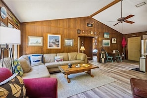 A cozy living room with a sectional sofa, a coffee table, and a ceiling fan. - Adorable 4 BR, short walk to the beach in Southern Shores! (Southern Shores)