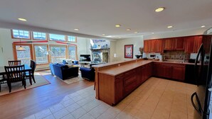 A spacious kitchen with a large island, wooden cabinets, and a dining area with a table and chairs. - SH3 Luxurious Stonehill Townhouse in Bretton Woods with Magnificent Views, Dog Friendly! (Bretton Woods)