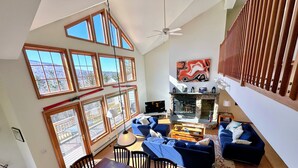 A spacious living area with a high ceiling, large windows, a fireplace, and a dining area. - SH3 Luxurious Stonehill Townhouse in Bretton Woods with Magnificent Views, Dog Friendly! (Bretton Woods)