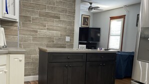 Una cocina moderna con armarios oscuros, suelo de madera, una isla integrada y un refrigerador de acero inoxidable.