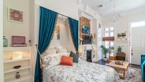 Een slaapkamer met een bed, een televisie, een open haard en een boekenkast.