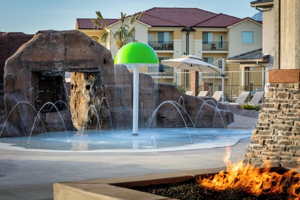 A water feature with a green ball, a fire pit, and a pool area with lounge chairs.