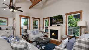 A spacious living room with a fireplace, large windows, and a ceiling fan. - What a View: Wake Up to the Wow (Gatlinburg)