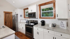 A kitchen with white cabinets, a stainless steel refrigerator, a microwave, an oven, and a coffee maker. - What a View: Wake Up to the Wow (Gatlinburg)