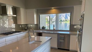 Una cucina moderna con una grande isola, elettrodomestici in acciaio inossidabile e vista su un lago.