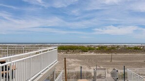 Blick auf die Küste mit einem weißen Gebäude, einem Sandstrand und spärlicher Vegetation.