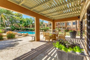 A covered outdoor area with a pool, lounge chairs, and potted plants. - Dog Friendly - 2 Patios Heated Pool, Spa & Fitness (Scottsdale)